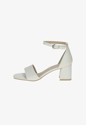 Sandale blanche à talon bloc avec une large bride avant et une bride à la cheville, dotée d'une boucle métallique et d'un matériau synthétique lisse.
