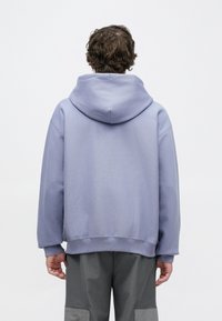 Camisola com capuz lilás claro, com capuz largo e arredondado, ombros caídos e bainha canelada. Tecido macio com textura suave e corte descontraído.