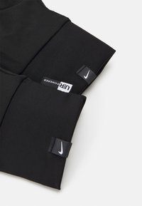 Black athletic vest with a smooth, fitted design. Features Nike branding and contrasting tags. Made from stretchy, durable fabric.