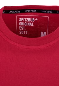 Rotes Baumwoll-T-Shirt mit Rundhalsausschnitt, innen mit einem Etikett versehen, das "SPITZBUB," "ORIGINAL," "EST. 2017" und die Größe "M" zeigt. Der Text ist in Weiß.