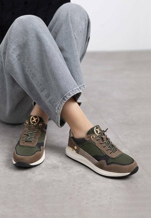 Des baskets vertes et marron avec un mélange de mesh et de daim, dotées d'une pointe ronde et d'un laçage. Des accents dorés et des détails noirs sont visibles.