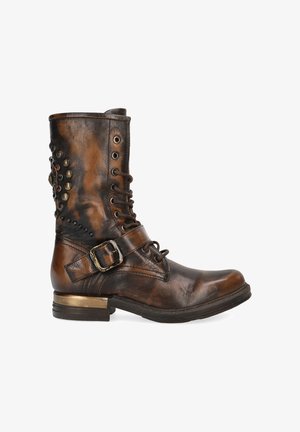 Brown leather ankle boot with a textured finish, lace-up front, side buckle, and decorative metal studs on the back. Low heel design.