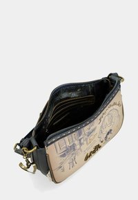 Texturierte Handtasche aus weichem Beige- und Navy-Leder mit grafischem Design, goldenen Beschlägen und mehreren Innenfächern zur Organisation.