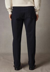 Dark gray trousers made of lightweight fabric, featuring two back pockets, straight-leg design, and subtle stitching details.