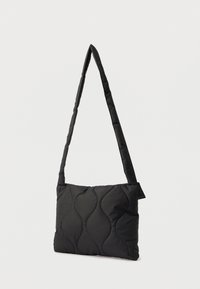 Crna kvačena torba za rame s dugim, glatkim remenom, koja na prednjoj strani ima teksturirani valoviti uzorak. Izrađena je od lagane tkanine.