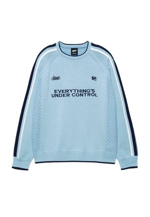 Világoskék kötött pulóver sötétkék és fehér csíkokkal az ujjain, valamint fekete felirat "MINDEN ELLENŐRZÉS ALATT" az elején.