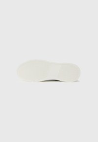 White sneaker sole with textured grip pattern, featuring a smooth surface and subtle wave detailing. Rounded shape, lightweight design.
