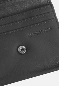 Black genuine leather wallet with multiple card slots, textured surface, and metal snap closure detail. Embossed "Genuine Leather" label.