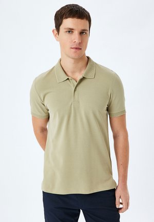Camisa polo verde oliva con cuello texturizado, mangas cortas y tres botones. Tejido suave con un diseño ajustado.