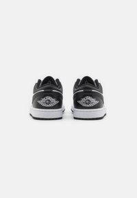 Czarne skórzane sneakersy z białymi podeszwami. Posiadają wyraźne logo Air Jordan na pięcie z designem skrzydeł. Zawierają teksturowane panele.