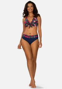 Góra bikini w kwiatowy wzór z wiązaniem z przodu, granatowy dół z kwiatowymi akcentami. Posiada krój na szyję, dopasowaną sylwetkę i gładką fakturę.