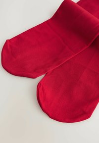 Red cotton socks, featuring a smooth texture, rounded toes, and a simple design, laid flat against a light background.
