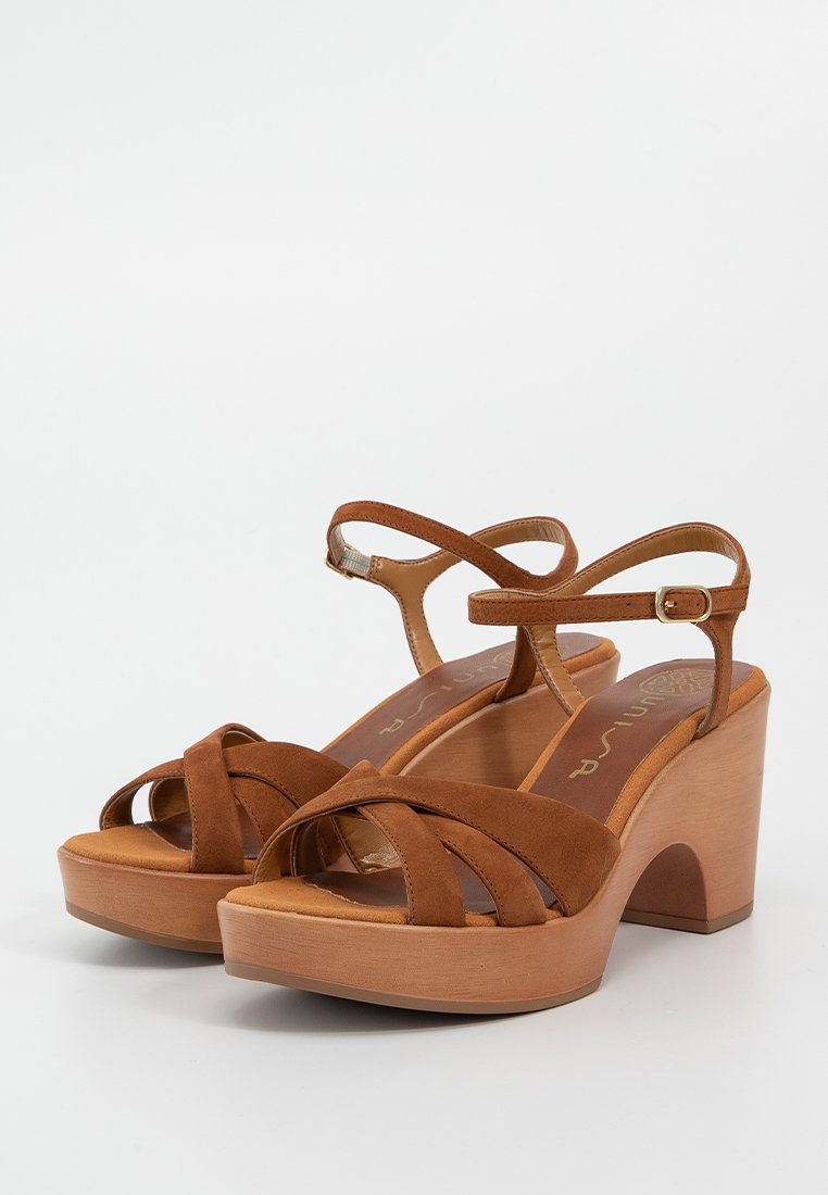 Sandales à plateforme en suède marron avec des lanières croisées, une bride à la cheville et un talon en bois. Texture lisse et design minimaliste.