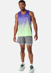 Lilla og grøn gradient tanktop med abstrakte mønstre, parret med grå shorts; atletiske sko med neon accenter.