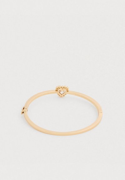 Kuldsetest banglitest koosnevad käevõrud, millel on sile viimistlus ja dekoratiivne kroonikuju keskel südamekujuga vääriskiviga. Reguleeritav kinnitussüsteem mugavaks kandmiseks.