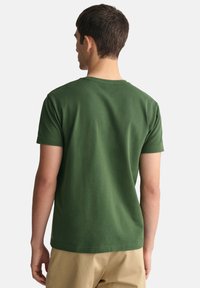 T-shirt in cotone verde con collo a giro e maniche corte. Tessuto liscio, design semplice e senza motivi o loghi visibili.