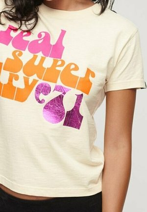 Haut court à manches courtes beige avec un texte audacieux de style rétro en lettres roses, orange et violet métallisé sur le devant.