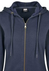 Hoodie zippé marine en tissu doux, avec une fermeture éclair dorée, des cordons de serrage et une doublure intérieure contrastante. Coupe standard avec poches.