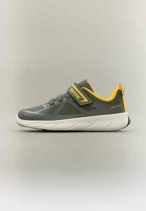 Chaussure de sport grise avec des accents jaunes, sangle velcro marquée "GEOX", semelle blanche et texte "water repellent" au talon.