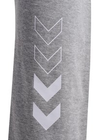 Grijze stof sweatpants met een verticale patroon van witte chevrons langs de zijkant. Het materiaal heeft een gladde en zachte textuur.