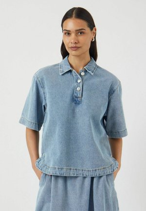 Denim chambray top met een kraaghalslijn, korte mouwen en knoopsluiting. Heeft een lichte rafeling aan de onderrand en is in een lichtblauwe kleur.