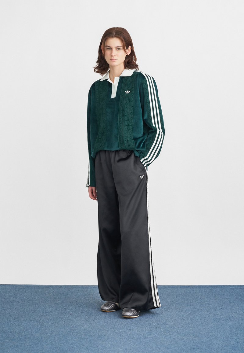 Green velvet long-sleeve top with white collar and textured pattern, paired with black wide-leg pants featuring white side stripes.