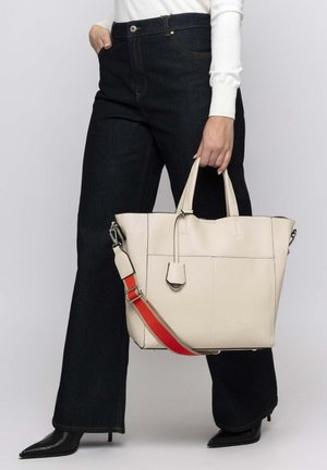 Beige leren tote bag met gestructureerde afwerking, voorzien van dubbele handvatten, een verstelbare rode schouderriem en een minimalistisch ontwerp.