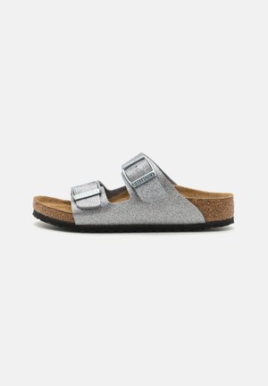 Sølvglitrende slide sandaler med to justerbare stropper, korkfodersåle og sort gummisål. Simpelt design med en tekstureret overflade.