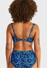 Blå blommig bikini-set med ett mönstrat topp med justerbara axelremmar och högmidjade trosor. Tyget har en mjuk, stretchig textur.