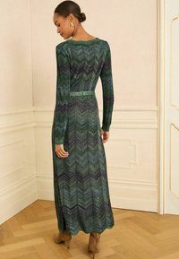 Pikend varrukatega kleit rohelise ja lilla chevron-mustriga, millel on vormitud vöökoht ja ümar kaelus, valmistatud tekstureeritud, elastses kangas.