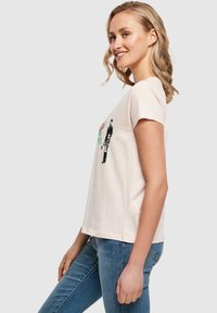 Kortærmet, lyserød bomulds T-shirt med grafisk tryk af en person og blomstrede elementer. Blød tekstur med en afslappet pasform.