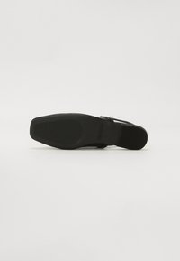 Sandale noire avec une semelle plate, un extérieur en cuir lisse, des fines lanières et un fond texturé pour l'adhérence. Design simple avec un minimum de détails.