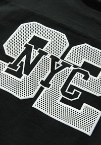 Černá mikina s velkými bílými perforovanými čísly "00" a "NYC" v tučném písmu, s texturovaným povrchem.