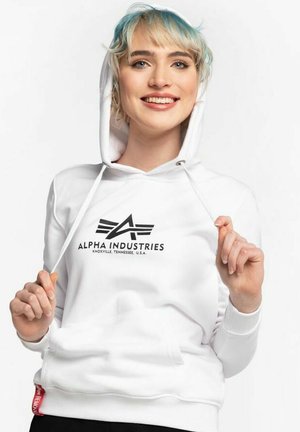 Bijela hoodie s prednjim kenguruvim džepom, kapuljačom s vrpcom i crnim logotipom s krilima. Mekana tkanina s glatkom teksturom.