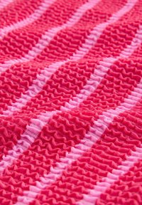 Tissu aux nuances variées de rose, présentant une texture froncée avec des motifs rayés alternés de roses plus foncés et plus clairs.