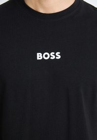 Schwarzes Baumwoll-T-Shirt mit Rundhalsausschnitt und weißem "BOSS"-Logo auf der Vorderseite. Weicher Stoff, lässige Passform.