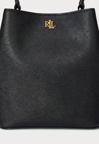 Musta käsilaukku, jossa on teksturoitu materiaali, pyöreä yläosa, kultainen logoakseli "RLL" ja yksinkertainen, minimalistinen muotoilu.