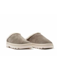 Grijze suede instappers met witte, pluizige voering en een beige rubberen zool met een gestructureerd profiel voor grip. Laag ontwerp.