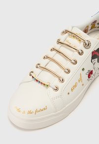 Sneaker bianca con accenti dorati, dotata di dettagli in gemme colorate e grafiche ricamate di un personaggio. Il testo sul lato recita "chi è il più bello?"