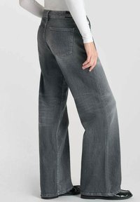 Jean en denim gris à jambe large avec une taille haute, doté d'une poche arrière avec un détail de logo de marque et un léger effet délavé. Devant plat sans ornements.