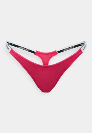 Czerwony bawełniany string z czarno-białą tasiemką z logo Calvin Klein, charakteryzujący się minimalistycznym designem i gładką teksturą.
