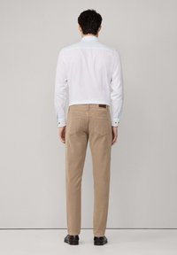 Witte overhemd met knopen en contrasterende blauwe accenten, gecombineerd met beige broek. Minimalistisch design met normale pasvorm en een soepele stofstructuur.