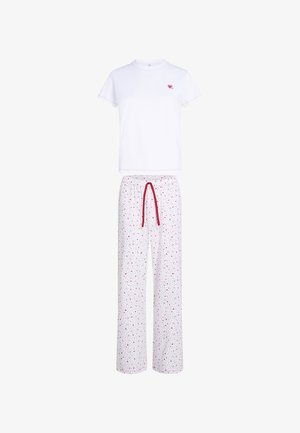 Witte pyjama-top met korte mouwen en klein hartlogo, met bijpassende witte broek met rode trekkoord en verspreid patroon van rode en zwarte hartjes.