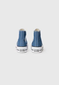 Blå canvas hög-top sneakers med vita gummisulor, med en rund logotyp på varje vrist och vita sömdetaljer.