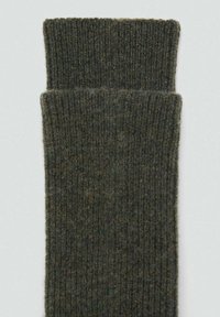 Calzini in maglia a coste di colore verde scuro, caratterizzati da una texture morbida e un risvolto piegato, progettati per calore e comfort.