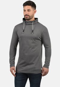 Grijze hoodie met lange mouwen, gemaakt van zacht materiaal, met een hoge kraag, verstelbare trekkoorden en een getailleerd ontwerp.