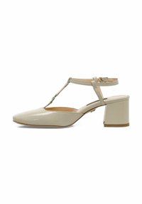 Talons en cuir verni beige avec une bride en T, bout pointu et talon carré. Présente un accent argenté sur la bride et une texture lisse et brillante.