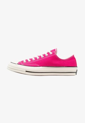 Pink canvas sneakers with white laces and stitching, low-top design, rubber sole, and black accent along the sole edge.