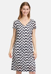 Kurzes Kleid mit einem navyblauen und weißen Zickzackmuster, V-Ausschnitt und lässiger Passform. Hergestellt aus leichtem Stoff mit texturierter Oberfläche.