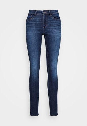 Dunkelblaue Skinny-Jeans mit vorderem Knopf und Taschen, mit Verblassungsdetails an den Oberschenkeln und Knien, vor einem schlichten weißen Hintergrund präsentiert.